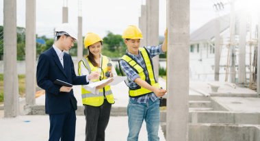 Mimar Asyalı takım inşaat alanında iş arkadaşlarıyla birlikte çalışıyor. Büyük projede mimarlık mühendisliği. İnşaat sürecinde bina içi.