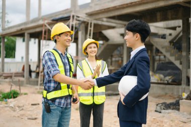 Mimar Asyalı takım inşaat alanında iş arkadaşlarıyla birlikte çalışıyor. Büyük projede mimarlık mühendisliği. İnşaat sürecinde bina içi.