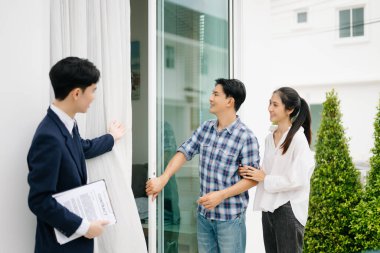 Asyalı emlak komisyoncusu, dosyasında ev detaylarını görmek isteyen Asyalı genç çifte gösteriyor. Yeni bir ev konsepti satın almak