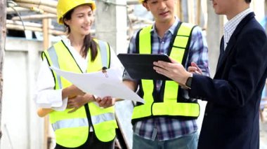 Mimar Asyalı takım inşaat alanında iş arkadaşlarıyla birlikte çalışıyor. Büyük projede mimarlık mühendisliği. İnşaat sürecinde bina içi.