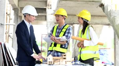 Mimar Asyalı takım inşaat alanında iş arkadaşlarıyla birlikte çalışıyor. Büyük projede mimarlık mühendisliği. İnşaat sürecinde bina içi.