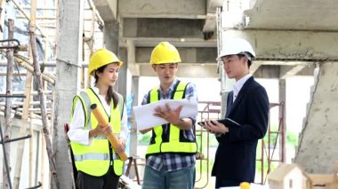 Mimar Asyalı takım inşaat alanında iş arkadaşlarıyla birlikte çalışıyor. Büyük projede mimarlık mühendisliği. İnşaat sürecinde bina içi.