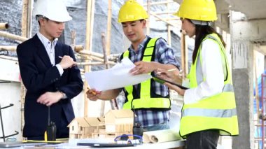 Mimar Asyalı takım inşaat alanında iş arkadaşlarıyla birlikte çalışıyor. Büyük projede mimarlık mühendisliği. İnşaat sürecinde bina içi.