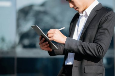 Dışarıda dijital tablet üzerinde çalışan kendine güvenen Asyalı işadamı