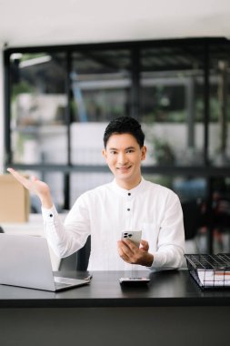 Modern ofisteki ahşap masada oturan yakışıklı genç adam.