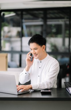 Modern ofisteki ahşap masada oturan yakışıklı genç adam.