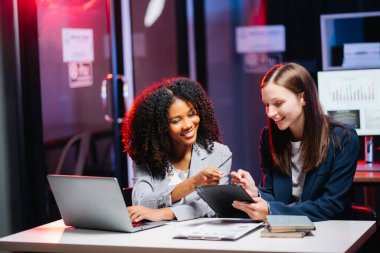 Ofiste çalışan genç iş kadınları tablet ve dizüstü bilgisayar kullanıyorlar. 