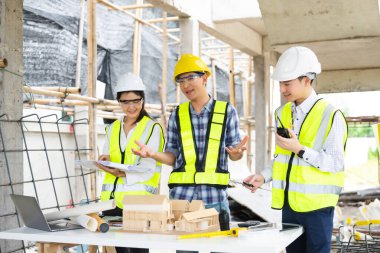 Mimar Asyalı takım inşaat alanında iş arkadaşlarıyla birlikte çalışıyor. Büyük projede mimarlık mühendisliği. İnşaat sürecinde bina içi.