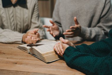 Bir grup Hıristiyan birlikte oturup ahşap bir masanın etrafında otururlar ve sınıfta bulanık incille dua ederler. Allah 'ın lütuf ve ihsanını dileyin..