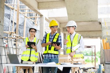 Mimar Asyalı takım inşaat alanında iş arkadaşlarıyla birlikte çalışıyor. Büyük projede mimarlık mühendisliği. İnşaat sürecinde bina içi.