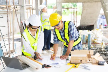 Mimar Asyalı takım inşaat alanında iş arkadaşlarıyla birlikte çalışıyor. Büyük projede mimarlık mühendisliği. İnşaat sürecinde bina içi.