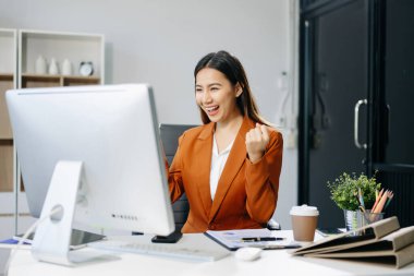 Genç, pozitif kadın muhasebeci bilgisayarını kullanarak ekiple konuşuyor.