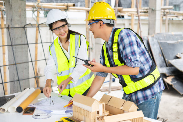 Архитектор азиатской команды работает с коллегами на строительной площадке. Архитектурное проектирование на большом проекте. Строительство интерьера в процессе строительства.