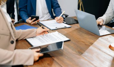 İş adamları ve avukatlar ofiste kontrat belgelerini tartışıyor ve dizüstü bilgisayar, akıllı telefon ve tablet kullanıyorlar. Hukuk ve adalet kavramı 