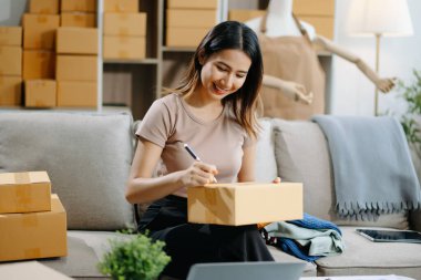 Genç iş kadını müşterilere çevrimiçi sipariş vermek için paket kutuları hazırlıyor. İnternetten alışveriş kavramı.