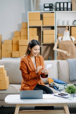 Genç iş kadını müşterilere çevrimiçi sipariş vermek için paket kutuları hazırlıyor. İnternetten alışveriş kavramı.