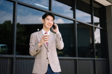 Genç Asyalı işadamı, lider, girişimci, profesyonel yönetici şehir merkezlerinde telefonla konuşuyor.