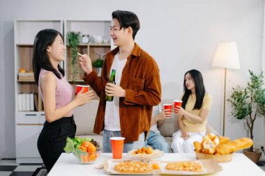 Bir grup Asyalı genç arkadaş evde akşam partisinin tadını çıkarıyorlar. Çekici genç erkek ve kadınlar eğleniyor, yemek yiyor ve içkiden zevk alıyor, modern evde kutlama yapıyorlar.