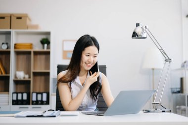 Genç ve çekici Asyalı ofis çalışanı takım elbiseleri modern ofiste dizüstü bilgisayar kullanıyor.