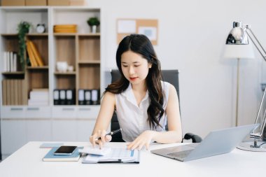 Başarılı Asyalı İş Kadını Tablet 'te Finans Analizi ve Modern Ofis Masasında Dizüstü Bilgisayar