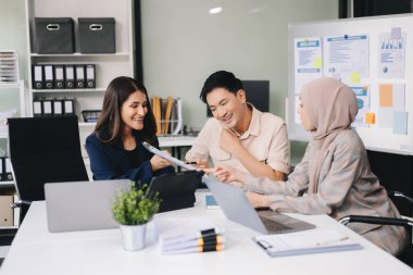 Modern ofis binasında iş planlarını tartışan bir grup genç Asyalı iş adamı