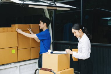 Express Teslimat Servisi. Asyalı kurye bayan müşteriye paket teslim ediyor. Deponun dışında kargo servisi, eve teslimat ve nakliye konsepti.