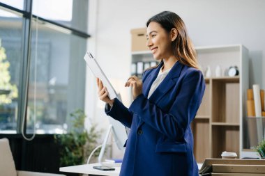 Yaratıcı ofiste dijital tablet üzerinde çalışan kendine güvenen bir iş kadını