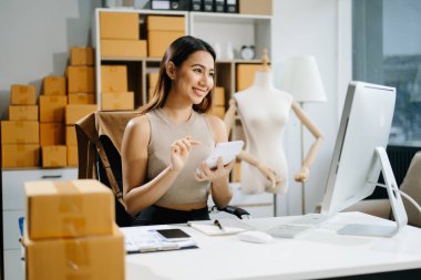 Genç iş kadını müşterilere çevrimiçi sipariş vermek için paket kutuları hazırlıyor. İnternetten alışveriş kavramı.