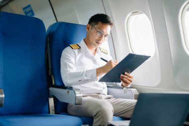 Asyalı kendinden emin, üniformalı erkek pilot uçuş planının yolcu koltuğunda.