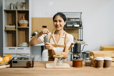 Profesyonel Asyalı barista kafede çalışırken kahve öğütüyor.