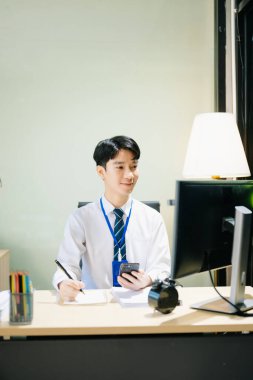 Genç Asyalı işadamı modern ofiste çalışıyor.