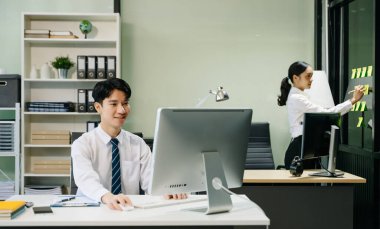 Modern ofiste çalışan Asyalı takım elbiseli genç ofis çalışanları.