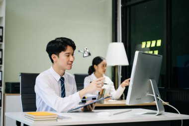 Modern ofiste çalışan Asyalı takım elbiseli genç ofis çalışanları.