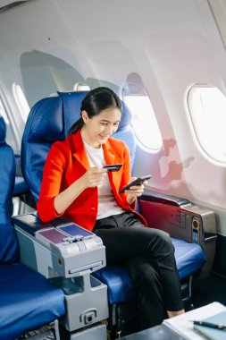 Çekici Asyalı kadın yolcu akıllı telefon kullanırken rahat koltukta oturuyor.