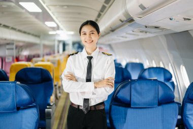 Asyalı kendinden emin, üniformalı kadın pilot uçağın içinde duruyor.