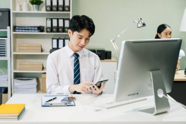 Genç Asyalı işadamı modern ofiste çalışıyor.