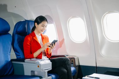 Çekici Asyalı kadın yolcu akıllı telefon kullanırken rahat koltukta oturuyor.