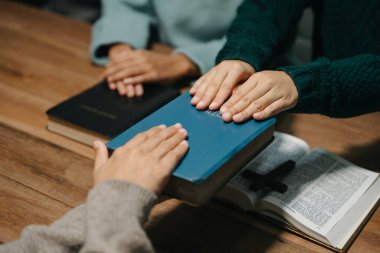 Bir grup Hıristiyan birlikte oturup odalarında açık İncil sayfaları olan ahşap bir masanın etrafında dua ediyorlar. Allah 'ın lütuf ve ihsanını dileyin..
