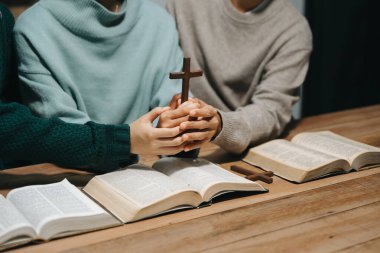 Bir grup Hıristiyan birlikte oturup odalarında açık İncil sayfaları olan ahşap bir masanın etrafında dua ediyorlar. Allah 'ın lütuf ve ihsanını dileyin..