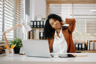 Çok çalışan Afrikalı Amerikalı iş kadını ofis çalışanı ofis masasında çalışırken yorgun hissediyor.