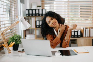 Çok çalışan Afrikalı Amerikalı iş kadını ofis çalışanı ofis masasında çalışırken yorgun hissediyor.