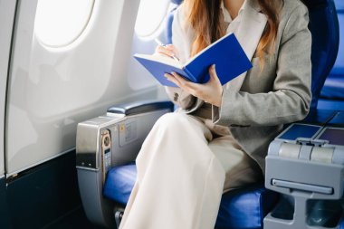 Birinci sınıftaki genç iş kadını not defterine notlar yazıyor. 