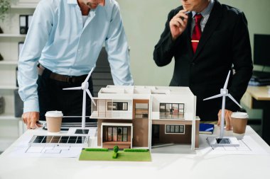 Bir iş toplantısının mimarları, modern bir yapı modelini planlamak ve tartışmak, mimari tasarımda takım çalışması ve yaratıcılığı sergilemek