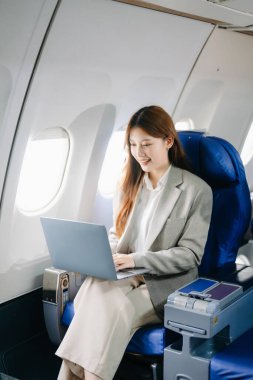 Genç Asyalı iş kadını dizüstü bilgisayar kullanarak uçakta birinci sınıfta. 