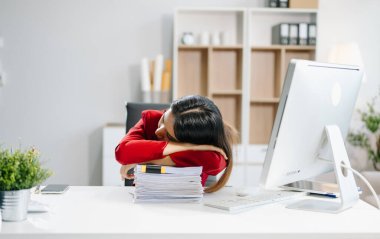 Çok çalışan Asyalı genç iş kadını ofis çalışanı ofis masasında uzun bir gün geçirdikten sonra uyuyor. ofis sendromu kavramı 