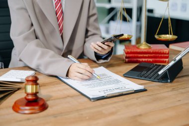 Adalet ve hukuk kavramı. Elinde tokmakla mahkeme salonunda akıllı telefon ve dijital tabletle çalışan erkek yargıç.
