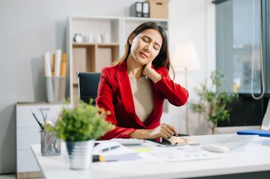 Ofis masasında uzun bir gün geçirdikten sonra boynu ağrıyan Asyalı genç işkadını ofis çalışanı. ofis sendromu kavramı