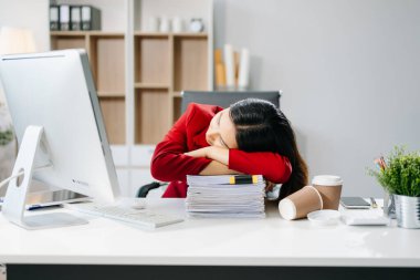 Çok çalışan Asyalı genç iş kadını ofis çalışanı ofis masasında uzun bir gün geçirdikten sonra uyuyor. ofis sendromu kavramı 