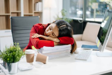 Çok çalışan Asyalı genç iş kadını ofis çalışanı ofis masasında uzun bir gün geçirdikten sonra uyuyor. ofis sendromu kavramı 