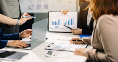 Ofisteki yeni projeyi tartışan ve çalışan meslektaşlar dizüstü bilgisayar ve dijital tablet kullanıyorlar 